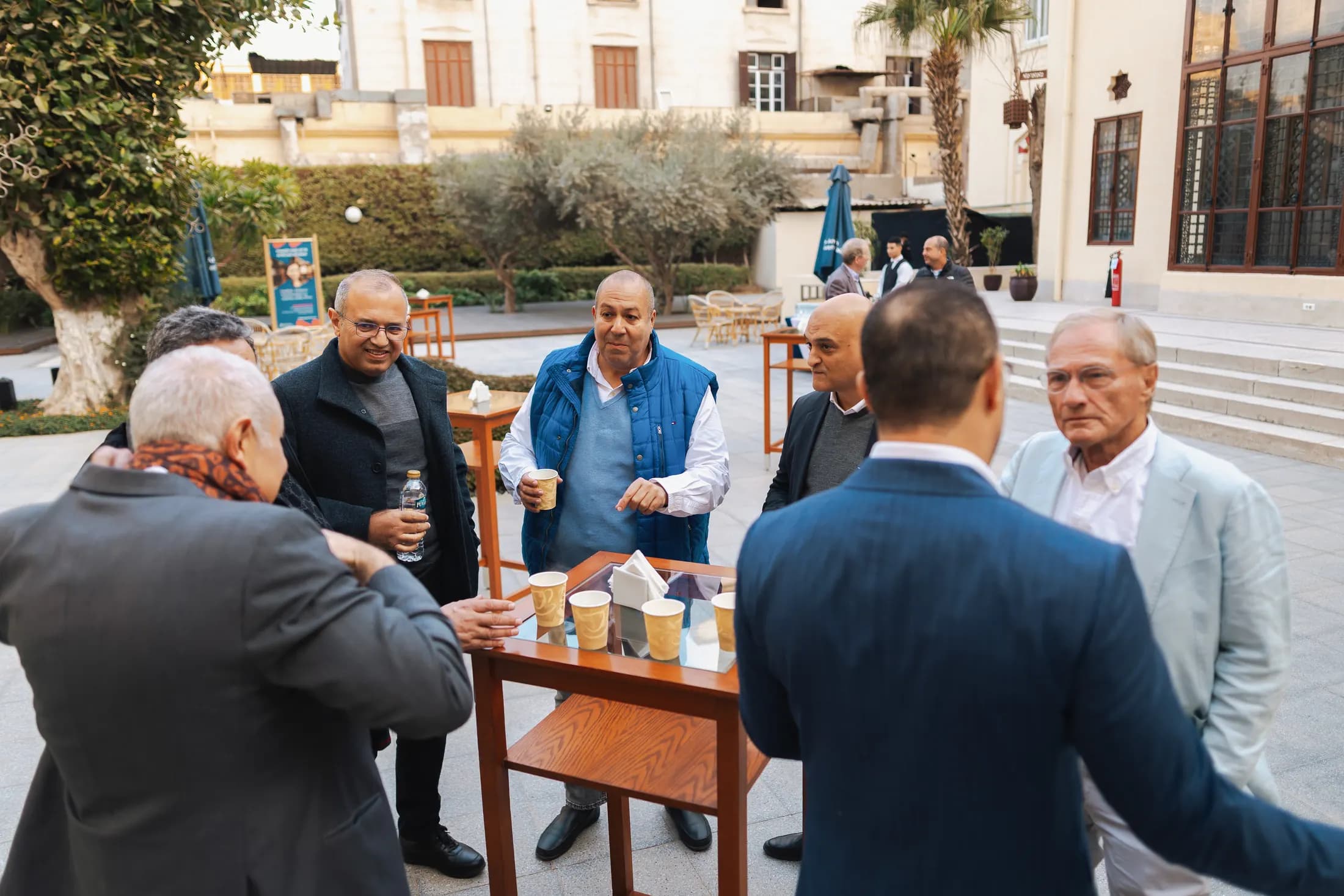 Members talking over coffee in a courtyard