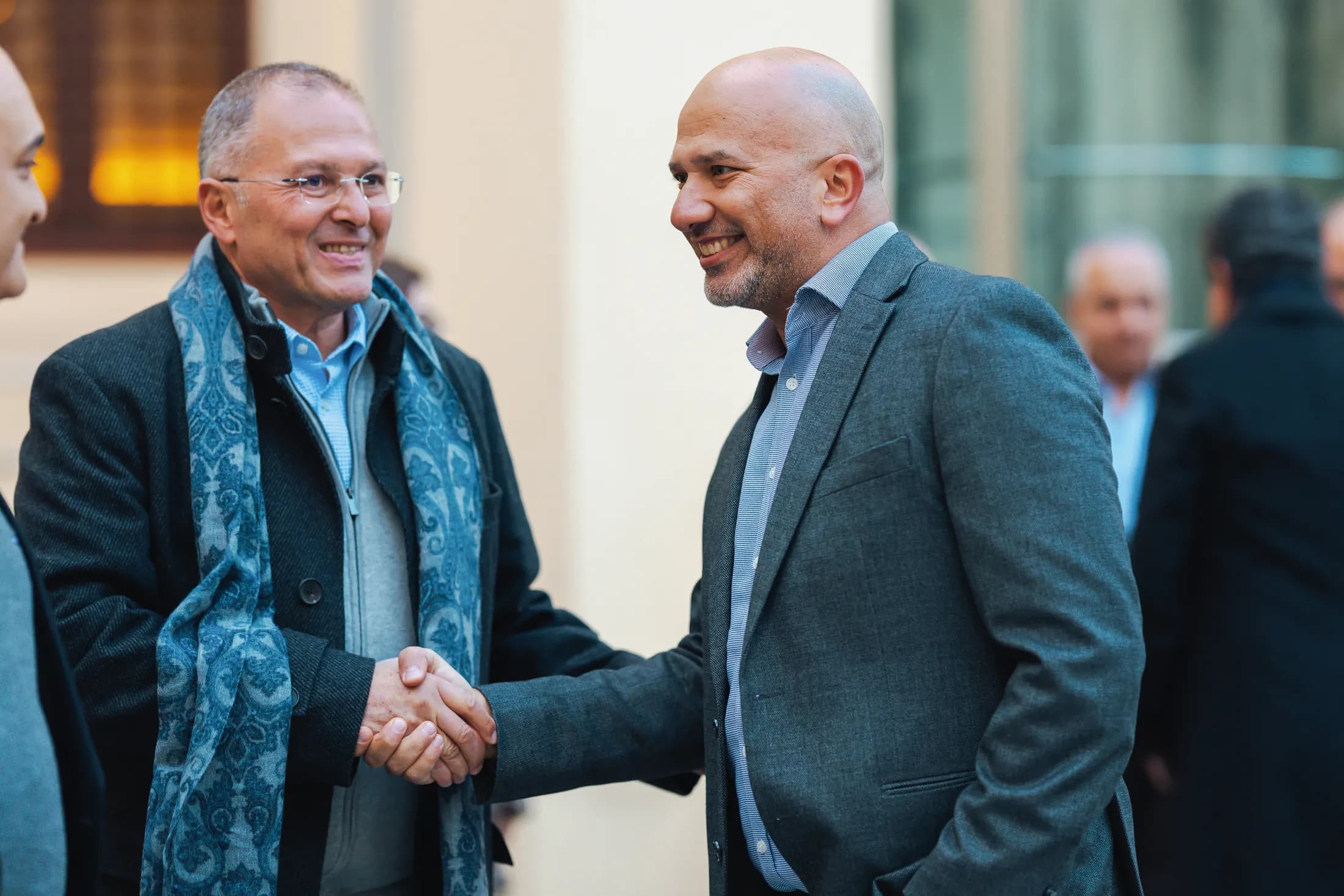 Two members shaking hands as they meet again